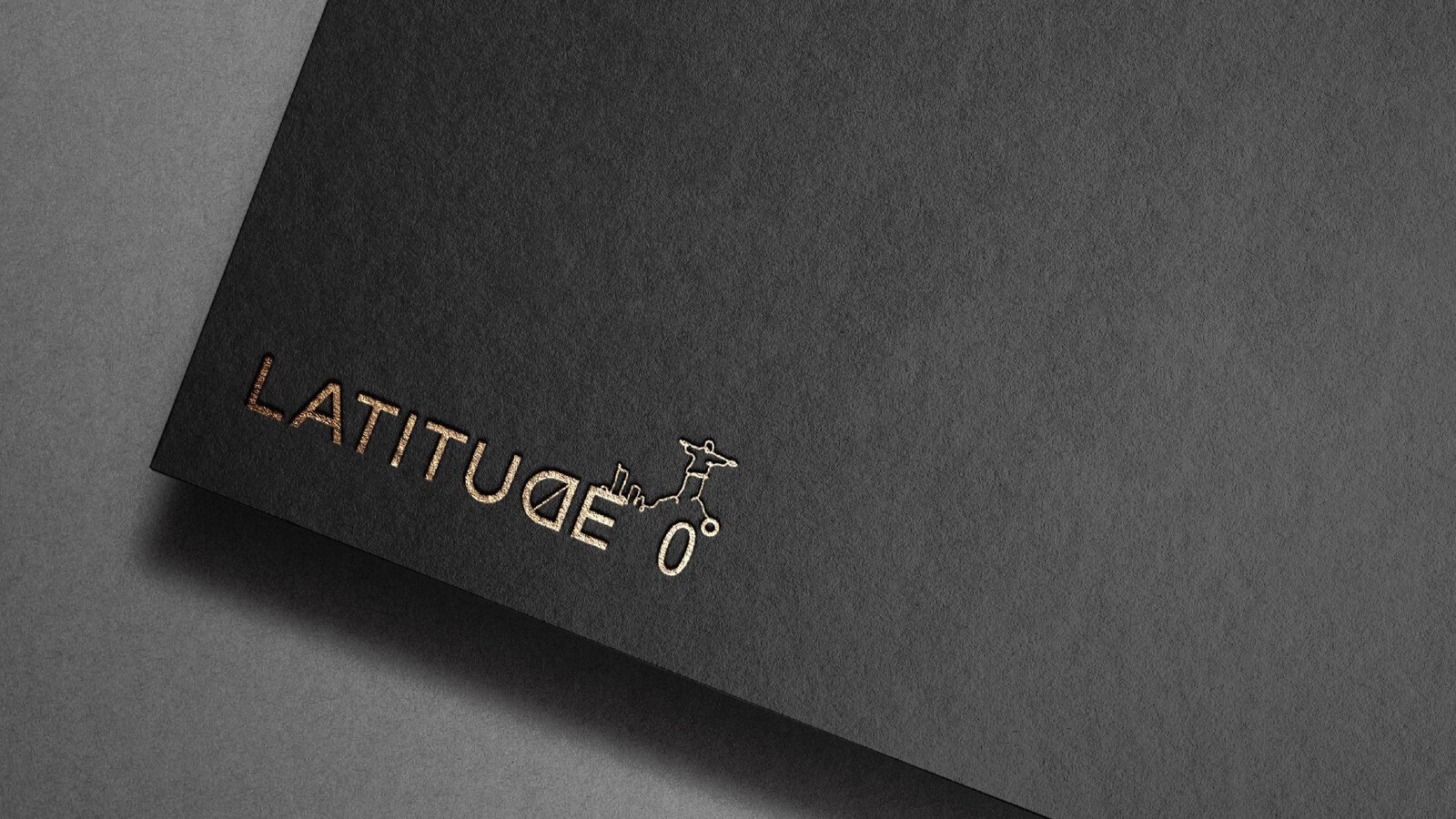 Logotipo de Latitude 0º estampado en dorado sobre papel negro